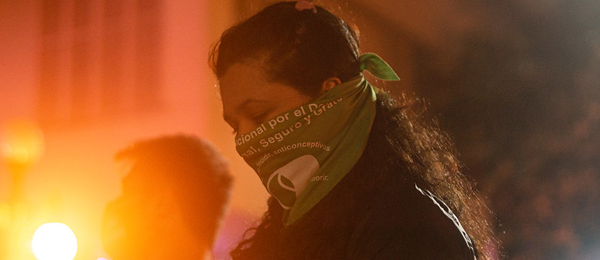 woman with scarf facemask at protest in latin america