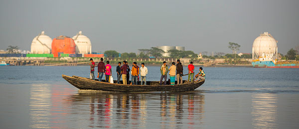 People on a boat in the Sundarbans in Bangladesh with Rampal coal based power plant construction site in the background.