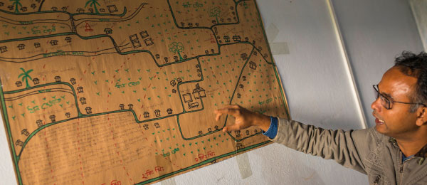 Bangladeshi man pointing at map of villages which use solar power
